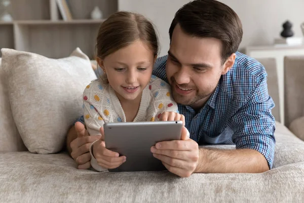 Menina criança pequena feliz e pai jovem usando tablet. — Fotografia de Stock