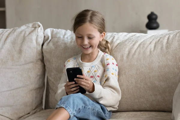 Happy little girl using cellphone at home. — стоковое фото