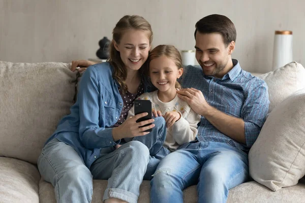 Cariñosos padres de pareja y su hija pequeña usando el teléfono celular. — Foto de Stock