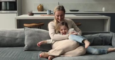 Güzel, genç, sevgi dolu anne küçük kızını gıdıklıyor.