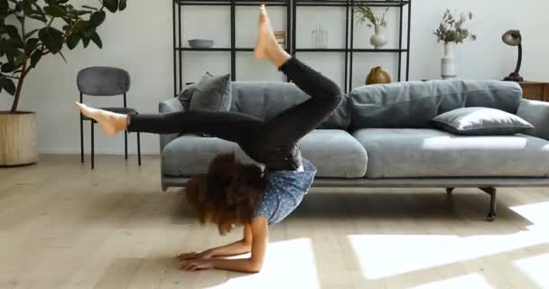 Cute little African curly haired girl practising yoga at home — стоковое видео