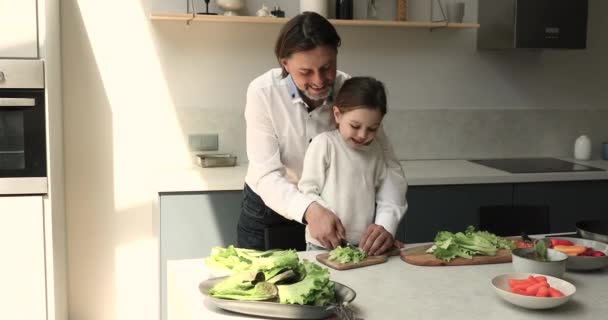 Любящий папочка учит маленькую дочь готовить здоровый овощной салат — стоковое видео