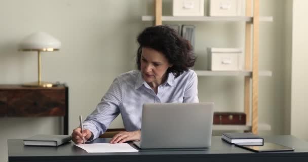 55s businesswoman sit at desk writing notes, texting on laptop — Video Stock