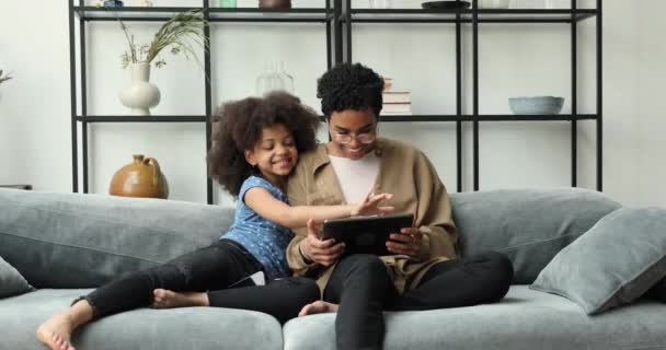 Klein meisje haar moeder ontspannen op bank met digitale tablet — Stockvideo