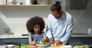 Genç Afrikalı baba ve küçük tatlı kız vejetaryen salatası hazırlıyorlar.