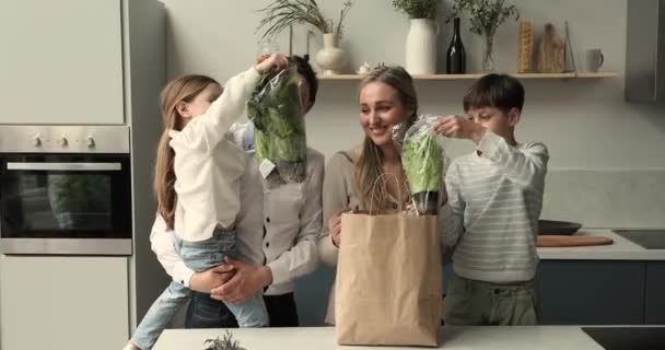 Familia con niños desempaquetar papel bolsa de compras con lechuga fresca — Vídeos de Stock