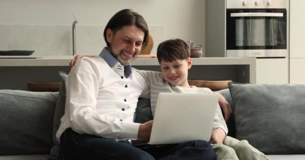 Carefree dad and son laugh watch funny cartoons use laptop — Stock Video