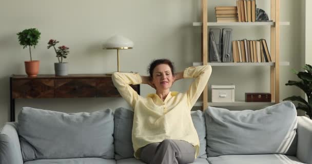 Starší žena relaxovat na gauči uvnitř útulný moderní obývací pokoj — Stock video