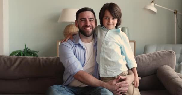 Happy young father sit on sofa cuddle with little son — 图库视频影像