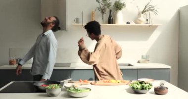 Mutlu Afrikalı çift mutfakta sebze salatası pişirirken dans ediyor.