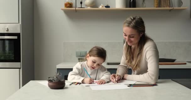 Genç bir kadın ve küçük bir kız mutfakta oturup resim yapıyorlar. — Stok video