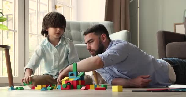 Young dad little son build castle from bright colored details — Vídeo de Stock