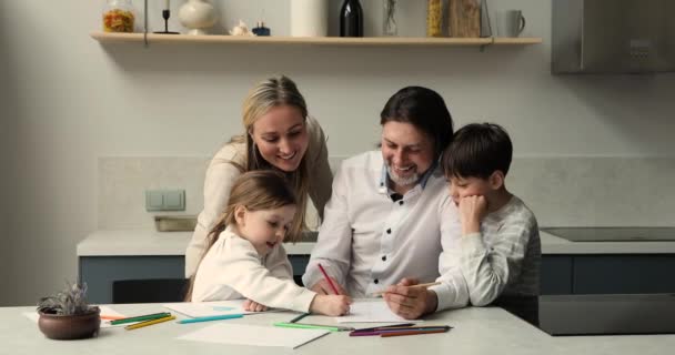 Famille avec enfants peignant des photos dans un carnet de croquis dans la cuisine — Video