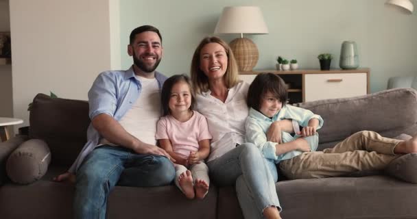 Щаслива здорова мама тато двоє дітей лоскоче сміючись на дивані — стокове відео