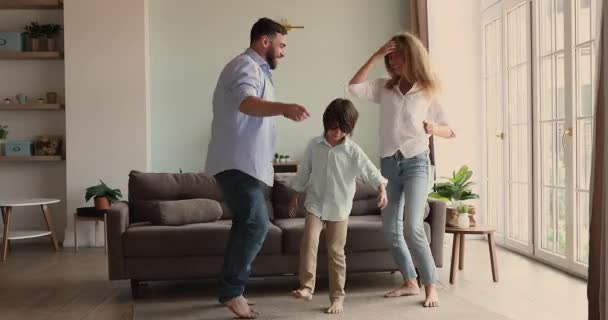 Happy family mother father son dancing barefoot at living room — Stockvideo