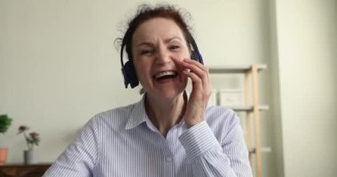 Olgun bir kadın iş yerinde oturup video konferansında konuşuyor.