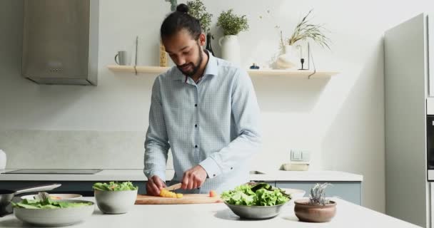 Afrikaanse man snijdt verse paprika bereiden salade voor gezond diner — Stockvideo