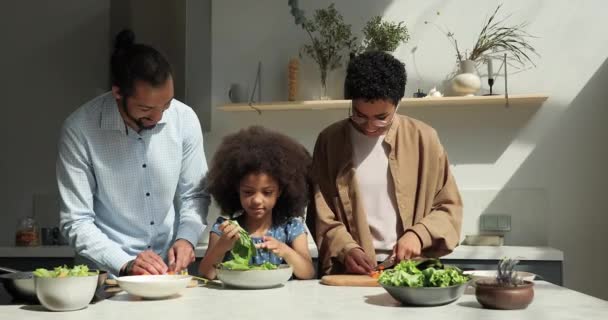 Familia vegana africana con hija preparan ensalada en la cocina — Vídeos de Stock