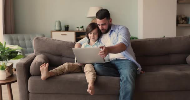 Zorgzame vader spelen video game op laptop met gelukkige zoon — Stockvideo