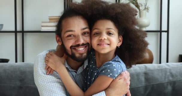 Loving African dad hugs daughter, family smile look at camera — стоковое видео