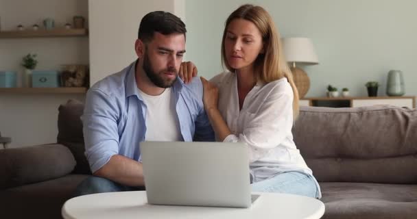 Genç çift kanepede sarılıp dizüstü bilgisayarla online piyango oynuyorlar. — Stok video