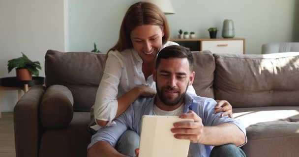 Affectionate girlfriend hug smiling boyfriend look on tablet screen — Vídeo de Stock