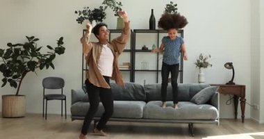 Afrikalı kadın küçük kızı dans ederek oturma odasında zıplıyor.