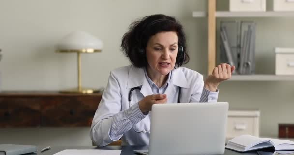 Senior female doctor consults client remotely use videocall app — Wideo stockowe