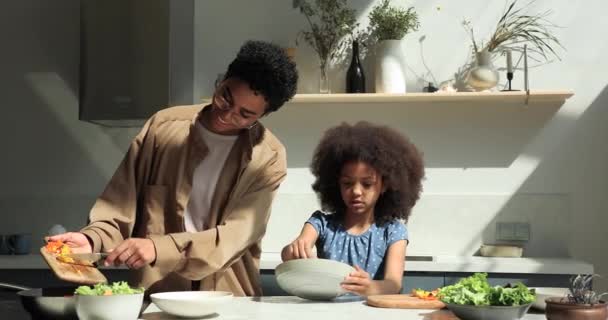 African woman her cute daughter cook together veggie salad — Wideo stockowe