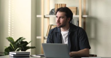 Odaklanmış adam çalışma masasına oturur ya da bilgisayar kullanır.