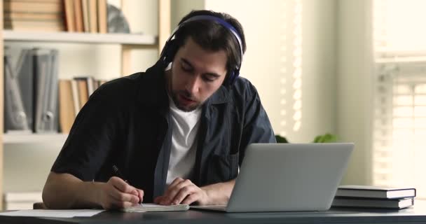 Guy wear headphones studying listens online tutor or audio course — стоковое видео