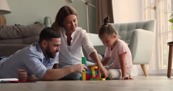 Mother father teach daughter preschooler to create buildings from constructor — Vídeo de Stock
