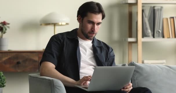 Man sit on couch working or shopping using laptop — Wideo stockowe