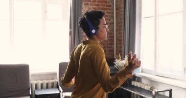 Evde dans eden Afrikalı kadın kulaklıkla en sevdiği şarkıyı dinliyor.