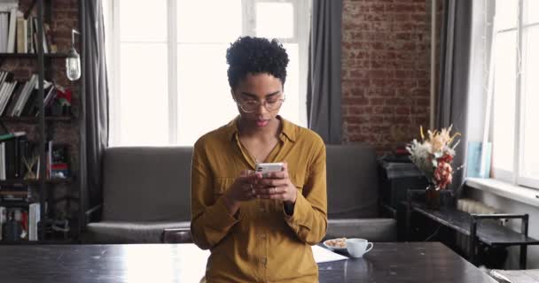 Young African woman holds cellphone chatting with friend online — Stock Video