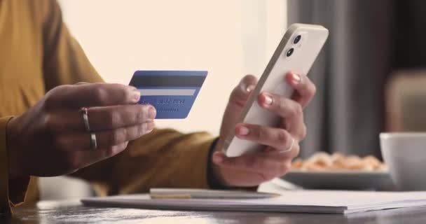 Primer plano manos femeninas sostiene el teléfono celular y la tarjeta comprar bienes en línea — Vídeo de stock