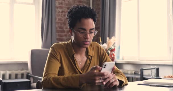 Mulher africana sentar à mesa detém mensagens de texto de telefone celular — Vídeo de Stock