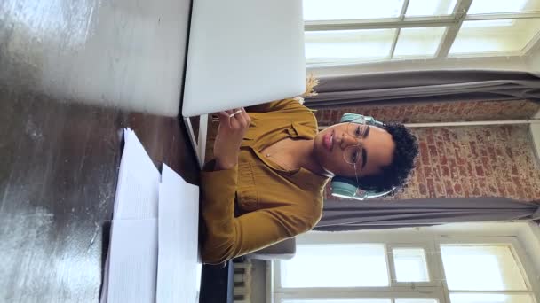 Жінка сидить за столом з ноутбуком, розмовляючи через відеодзвінок — стокове відео