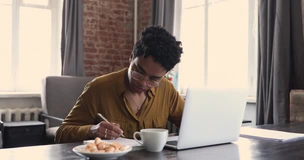 Afrikaanse vrouw gebruik laptop zoeken informatie, schrijft in copybook — Stockvideo