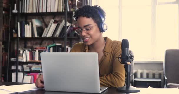 Женщина в наушниках смотрит на ноутбук и произносит речь в микрофон — стоковое видео