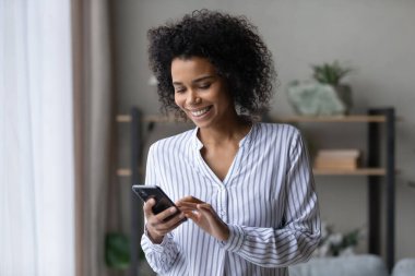 Akıllı telefon uygulamaları kullanarak gülümseyen Afrikalı genç bir kadın..