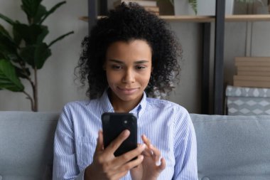 Gülümseyen genç Afrikalı kadın evde telefonla konuşuyor..