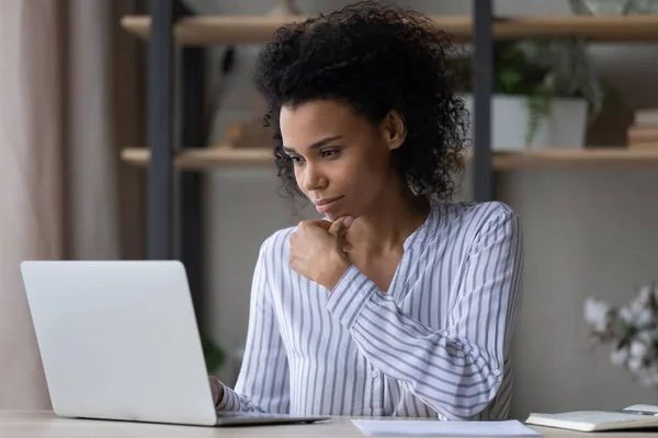 Jeune femme d'affaires africaine d'ethnicité réfléchie travaillant sur ordinateur. — Photo