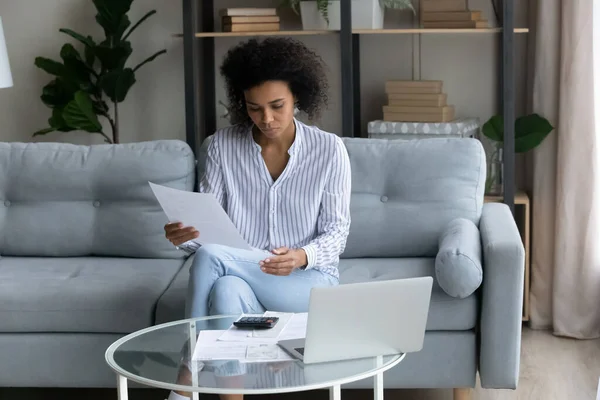 Gerichte duizendjarige Afrikaanse vrouw die rekeningen thuis berekent. — Stockfoto