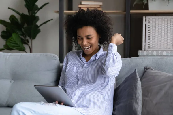 Oververheugd jonge Afrikaanse etniciteit vrouw vieren online loterij te winnen. — Stockfoto