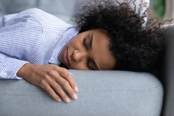थका हुआ युवा अफ्रीकी अमेरिकी महिला सोफा पर सो रही . — स्टॉक फ़ोटो, इमेज