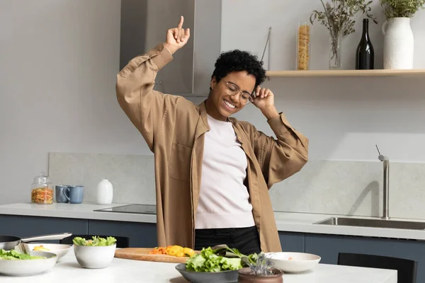 Feliz mujer emocionada bailando en la mesa de la cocina con ensalada —  Fotos de Stock