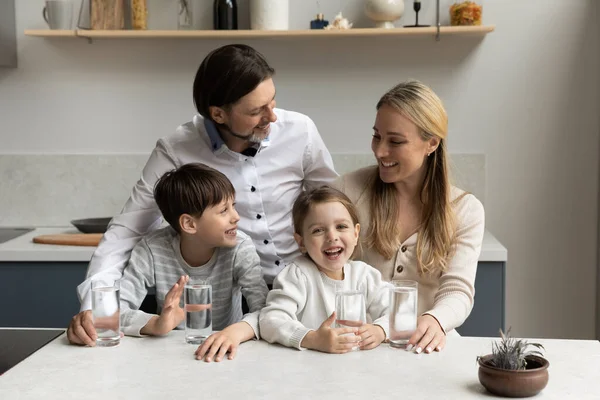 Happy parents and two healthy sibling kids drinking water — стоковое фото