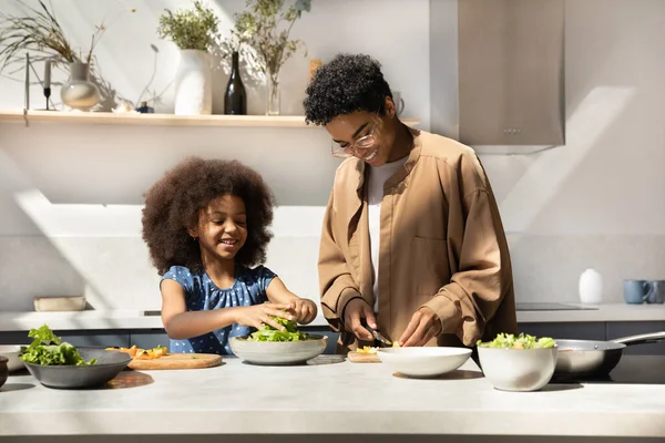 Happy African American mom and daughter girl preparing dinner together — Fotografia de Stock