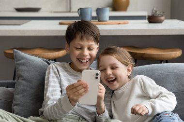 Mutlu neşeli kardeş çocuklar akıllı telefondan komik medyayı izliyor.